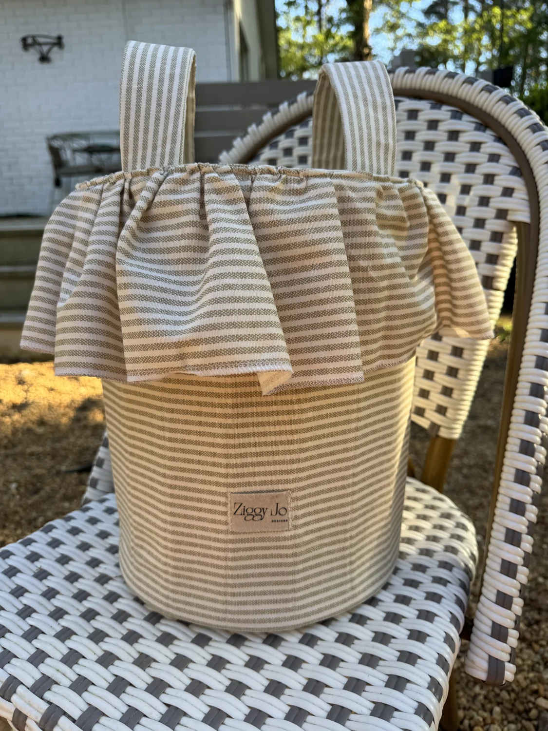 Daisy Stroller Bag in yellow stripes on a woven chair