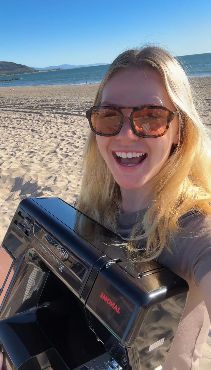 Molly smiling at the beach with a camera